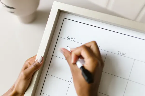 Man sieht Frauenhände, die einen Termin in einen Kalender eintragen